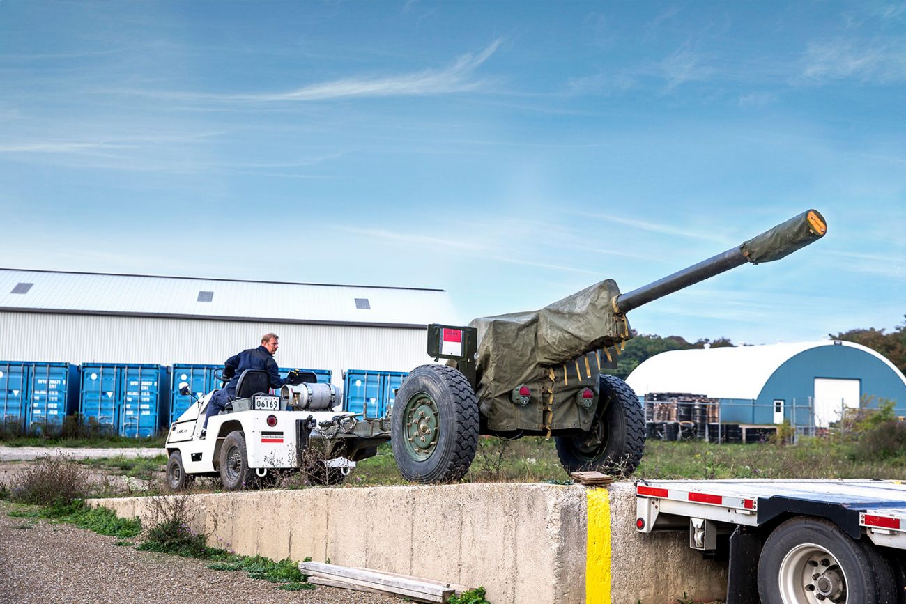 CBO_News-Image-Meaford-10-years-support-service-contract A CBO employee in a vehicle loading a Howitzer military gun onto a flatbed trailer.