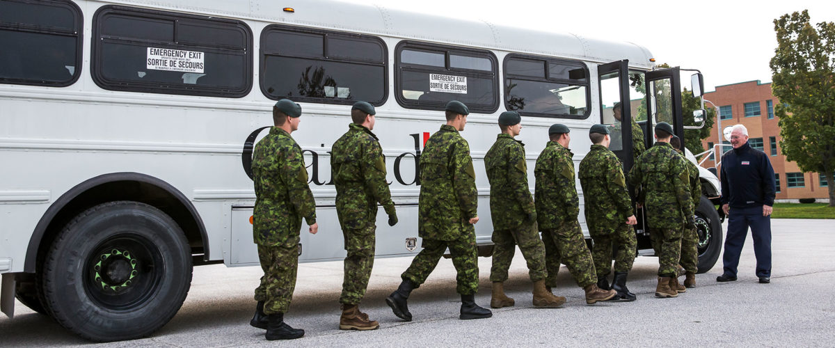 A group of troops line up and get on to the bus