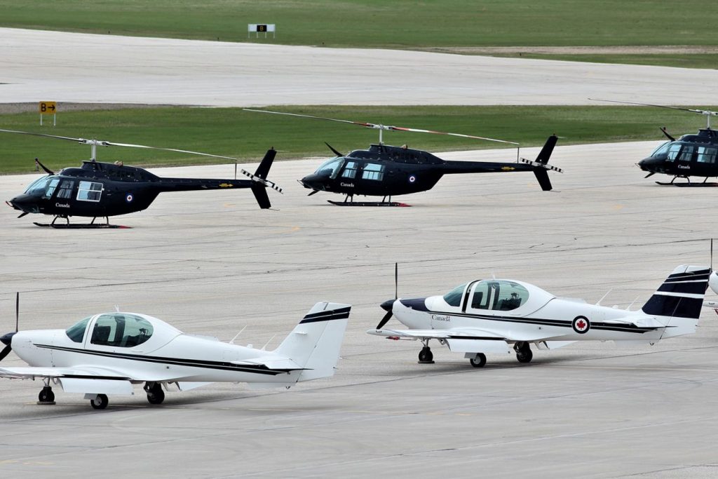 Three helicopters and two airplanes parked on a runway tarmac at CFTS Southport in Manitoba.