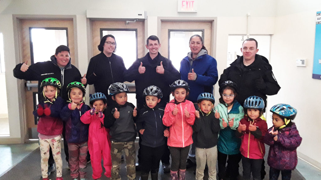 A group photo of children with new bike helmets giving a thumbs up in Inuvik, Northwest Territories.