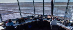 Three CBO employees in an air traffic control tower looking out onto the runway at CFTS Southport.