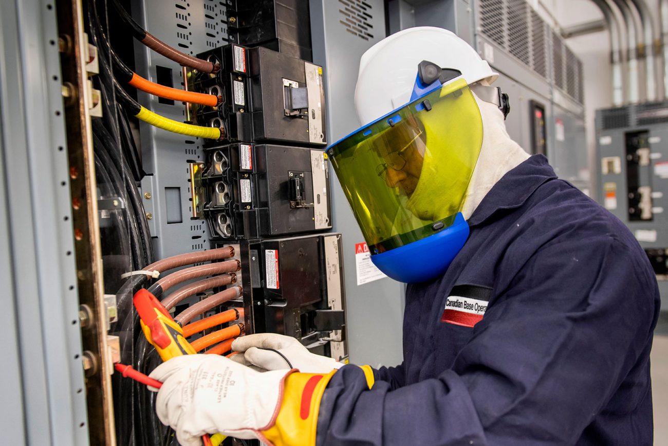 A CBO electrician wearing safety gear performing electrical maintenance and inspection services.